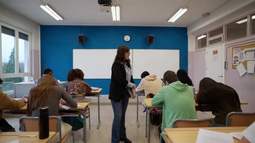 Teacher Supervises Students Taking a Test in Classroom