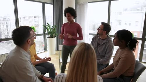Diverse group of people sitting in circle in group therapy session.
