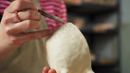 Woman Paints Ceramic Art with Paint Brush