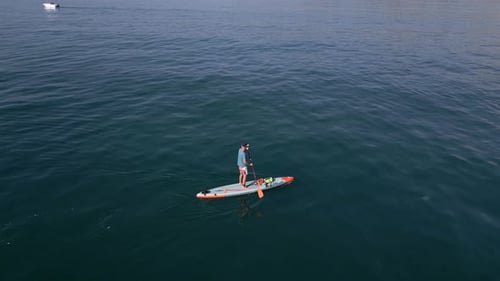 Aerial View of a Man Paddling a Standup Paddleboard or SUP Board on a Calm Sea