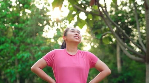 Young Asian woman in sportswear stretches before exercising in the park for a healthy lifestyle.