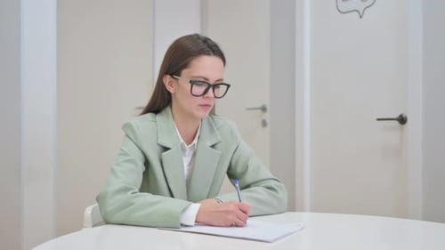 Young Woman Writing at Desk in Office