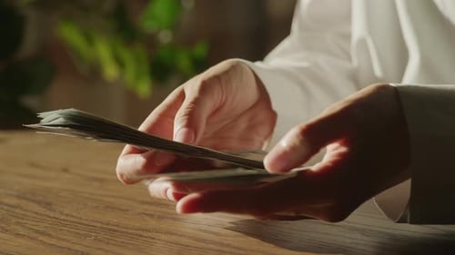 Counting Money with Hands on Wooden Table