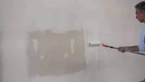 Man Paints Wall with Roller