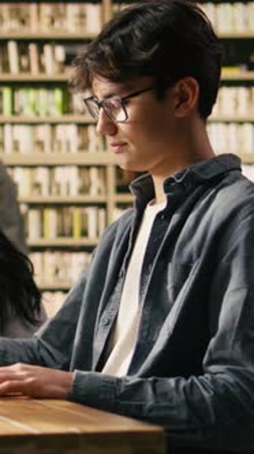 Vertical Video Side Profile of Student Reading Open Book at Quiet Library Table