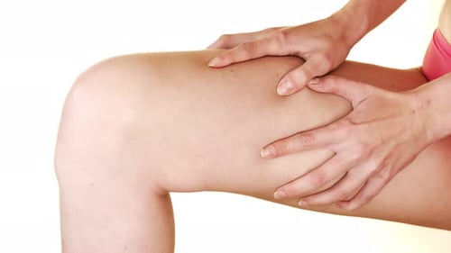 Woman massages thigh pain due to injury.