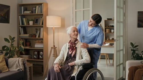 Caring Woman Assists Senior Woman in Wheelchair at Home