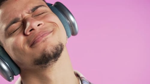 Young Positive Man Listening Music Enjoying with Headphones Pink Studio