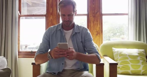 Smiling Man Using Mobile Phone at Home
