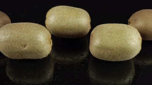 Four Kiwi Fruits on a Black Reflective Surface