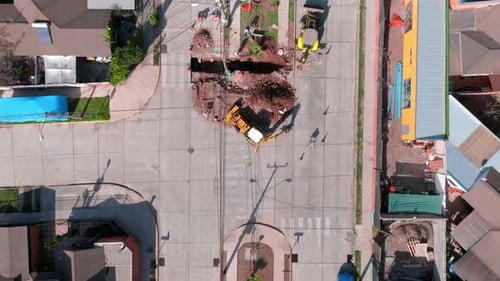 Overhead dolly in view of heavy machinery performing repair work on the public road in broad dayligh