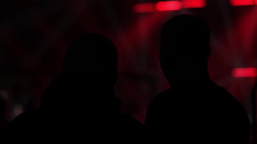 Silhouetted People in Dimly Lit Red Space
