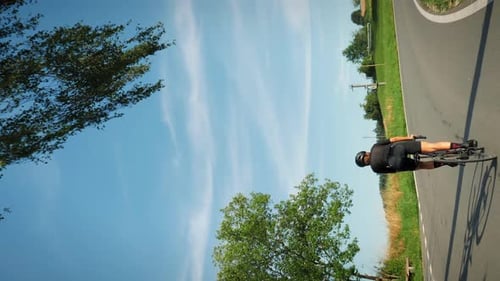 Cyclist riding road bicycle out of saddle, pushing hard pedals. Vertical video
