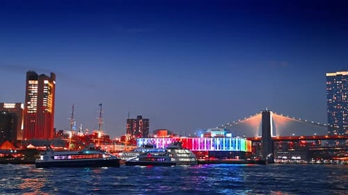 Os barcos de cruzeiro percorrem a paisagem aquática do East River à noite.