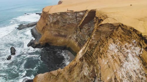 Orbital shot of huge cliffs at the ocean side, as birds flying to their nesting place