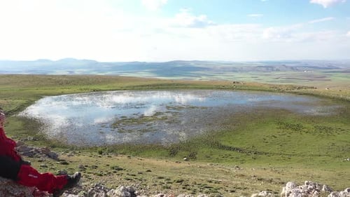 Vue aérienne d'une femme regardant autour d'elle sur le rocher au bord du lac