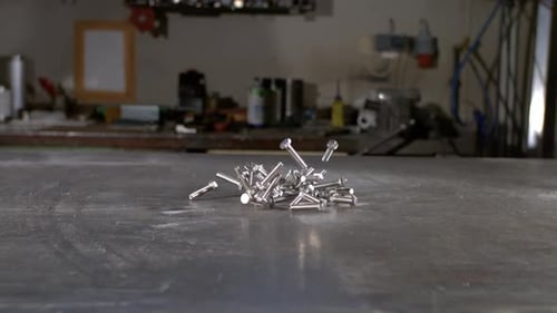 Shiny Metal Bolts Falling onto Workshop Surface