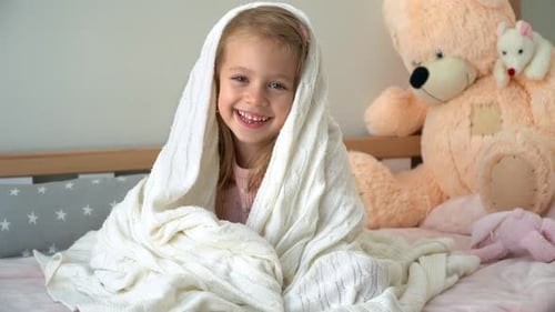 Girl in Bed Wrapped in Blanket Laughs Happy Child Plays and Fools