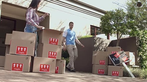 Woman and Man Unpacking Boxes Outside of House