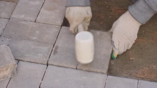Top View of Worker Laying Paving Stones with a Mallet Construction Tutorial