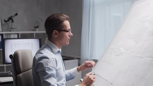 Architect Works in Loft Using Drawing Board Workplace of Young and Serious Engineer in Modern Office