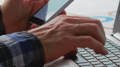 Hands Typing on Laptop While Using Cellphone