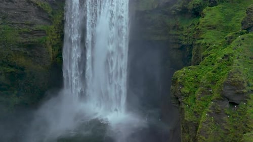 Majestic Waterfall Flowing Through Green Cliffs Aerial View