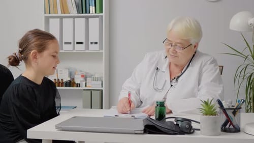 Female Family Doctor is Writing Down Child Medical Issues in a Health Clinic.