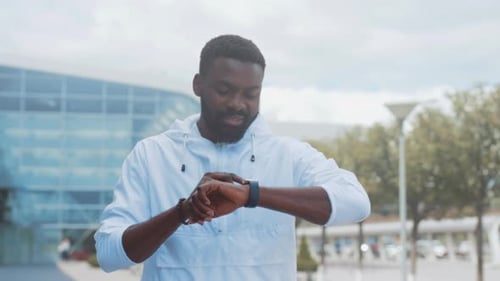 Man Outdoors Checks Smartwatch in Urban Park Setting