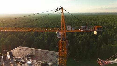 Construction Crane Overlooks Forest and Building Site at Sunset