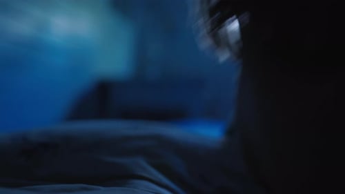 Tired child lying back onto pillow to sleep in dark room, closeup profile view