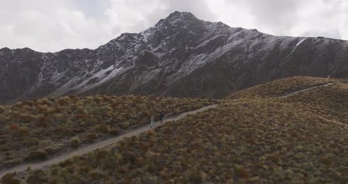 Couple hiking downhill from mountain with Ben Lomond snowy peak in background