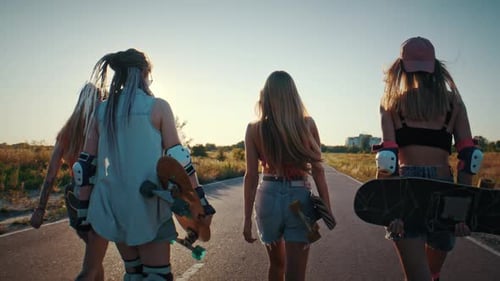 Young Women Stroll Together Along Rural Road During Sunset