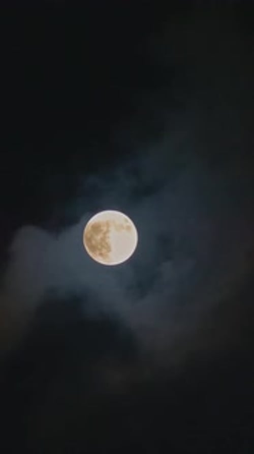 Vertikaler Mond, der sich zwischen Wolken bewegt