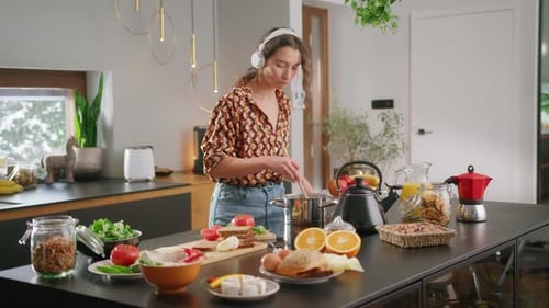 Woman Cooking with Headphones in a Bright Kitchen