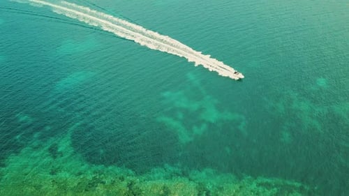 drone shot of motorboat cruising through the beautiful blue water of adriatic sea