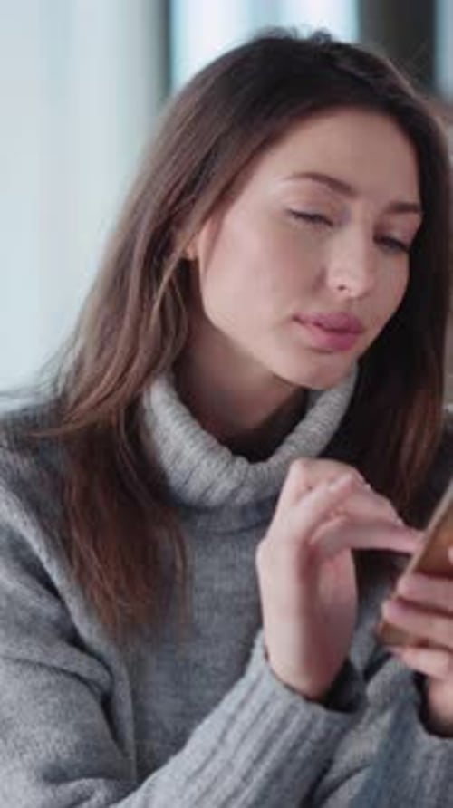 Woman Looks at Phone and Touches Screen Indoors