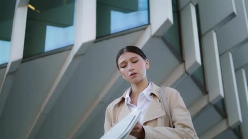 Serious Young Woman Reading Newspaper On City Street Close Up. Attractive Confident Business Lady...
