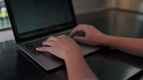 Close-up of hands typing on a laptop keyboard, showing the dedication and focus