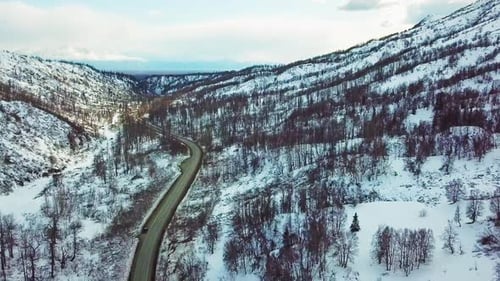 Flying toward exit of valley with snow covered hills and mountains.