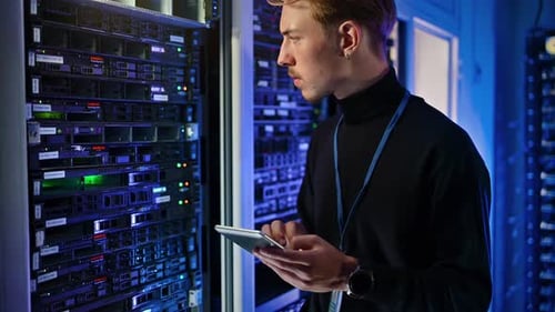 Young Adult Working on Servers in Data Center