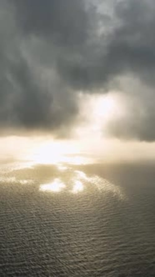 Vertikales Video-Luftdrama Bewölkter Sonnenuntergang über Meer und Stadt
