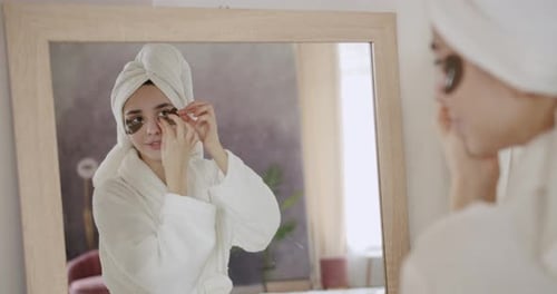 Woman Applying Eye Patches in the Mirror