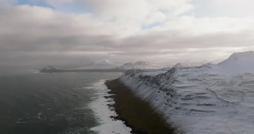 scenic icelandic landscape view on rocky shore ocean, snowy mountains and green grass