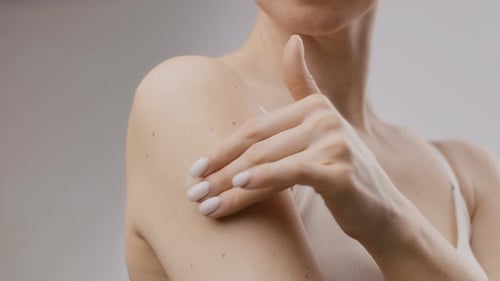 Woman Rubbing Cream on Arm and Shoulder