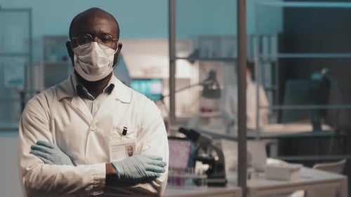 Confident Male Scientist Against Group of Colleagues Working in Laboratory