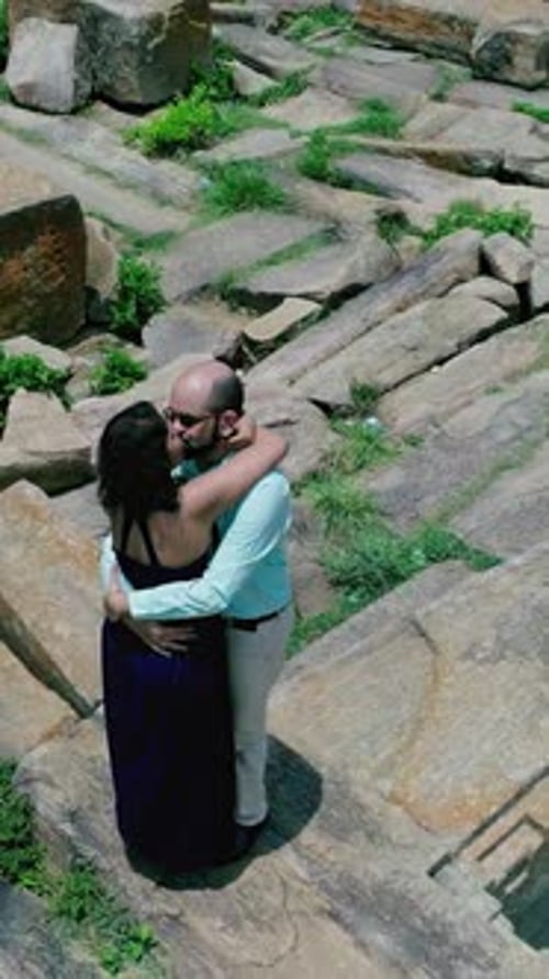 VERTICAL : Vue aérienne d'un couple marié alors qu'ils s'embrassent sur les ruines du complexe du temple de Raya Gopura