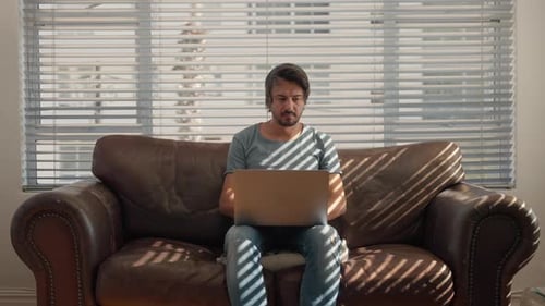 Young Adult Working on Laptop on Couch Indoors
