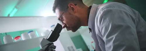 Man Looking Into Microscope In Modern Lab