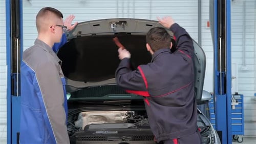 Deux mécaniciens ouvrent le capot de la voiture au service automobile